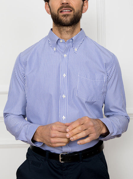 Man wearing long sleeved shirt with royal blue and white thin stripe made with 100% cotton from Thomas Mason.